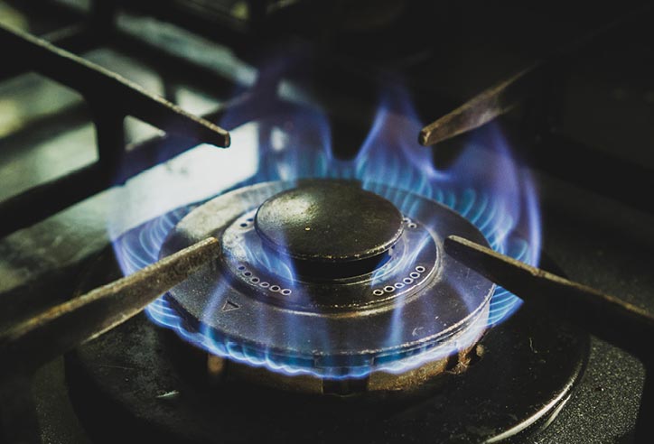 Close-up of a gas burner with a ring of blue flames on a cooker.